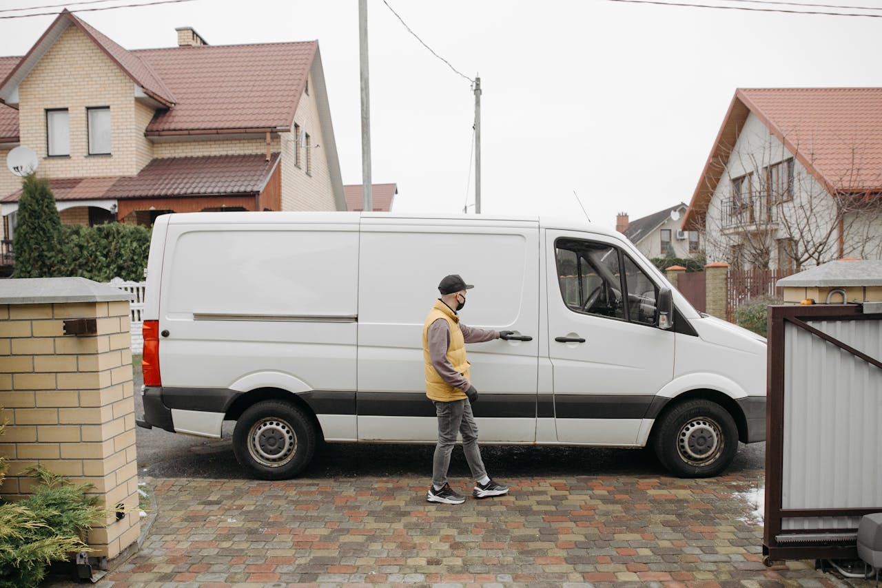 A delivery man exits his van in a suburban residential neighborhood for home delivery.